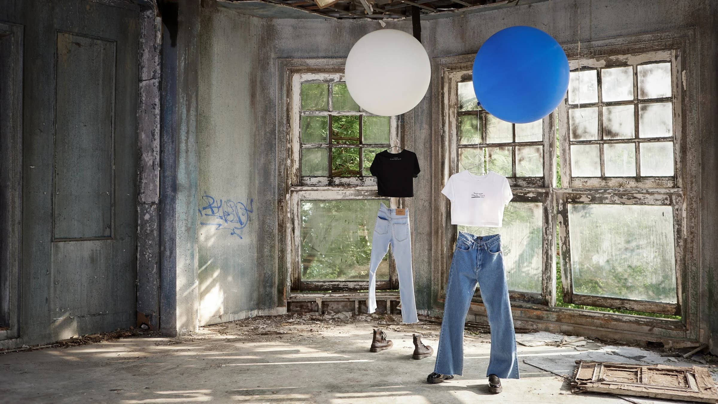 Two figures in Jack Russel denim holding oversized balloons in a derelict room